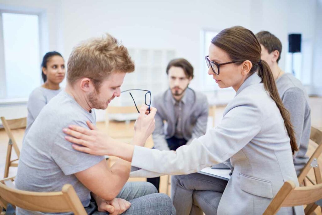 Young professional psychologist comforting one of managers during session